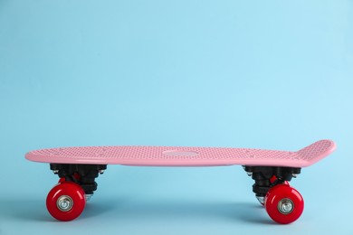 Photo of Pink skateboard on light blue background. Space for text