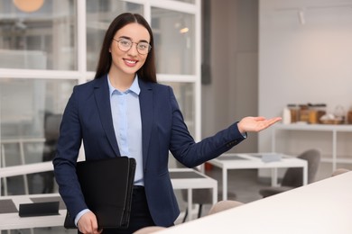 Photo of Happy real estate agent with leather portfolio in office