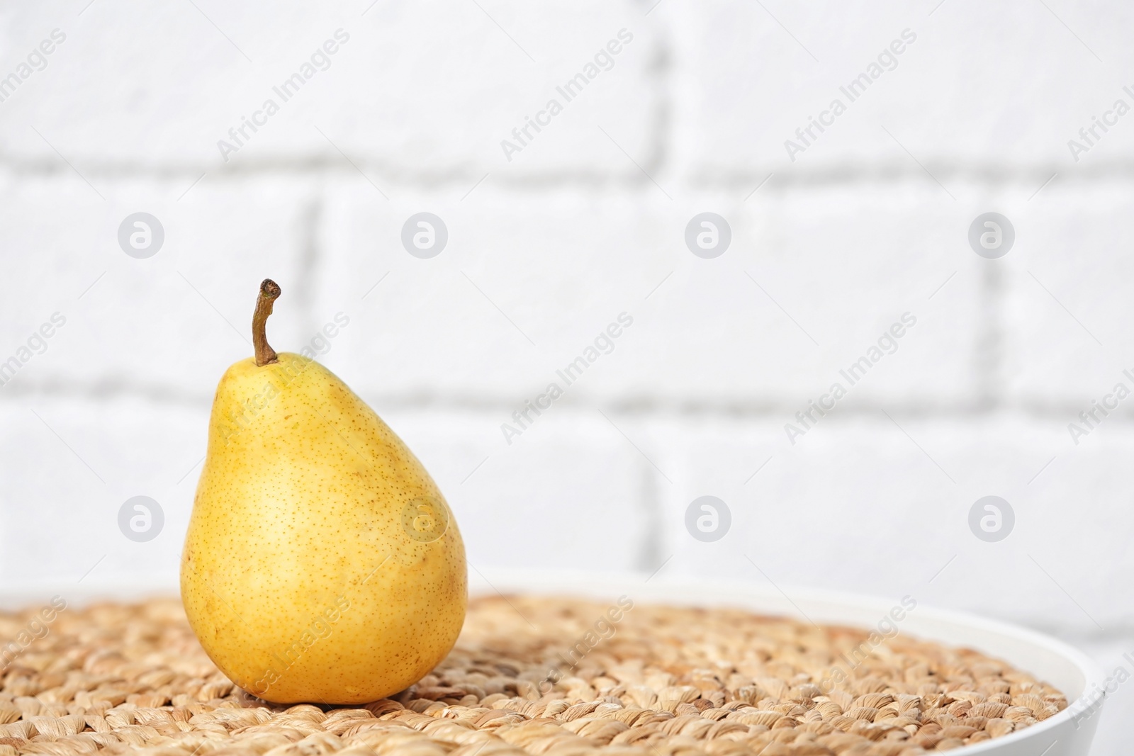 Photo of Ripe pear on table near brick wall. Space for text