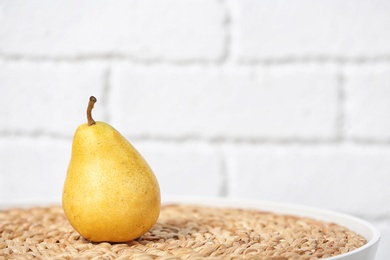 Ripe pear on table near brick wall. Space for text