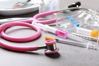 Photo of Stethoscope and syringes on grey table. Medical objects