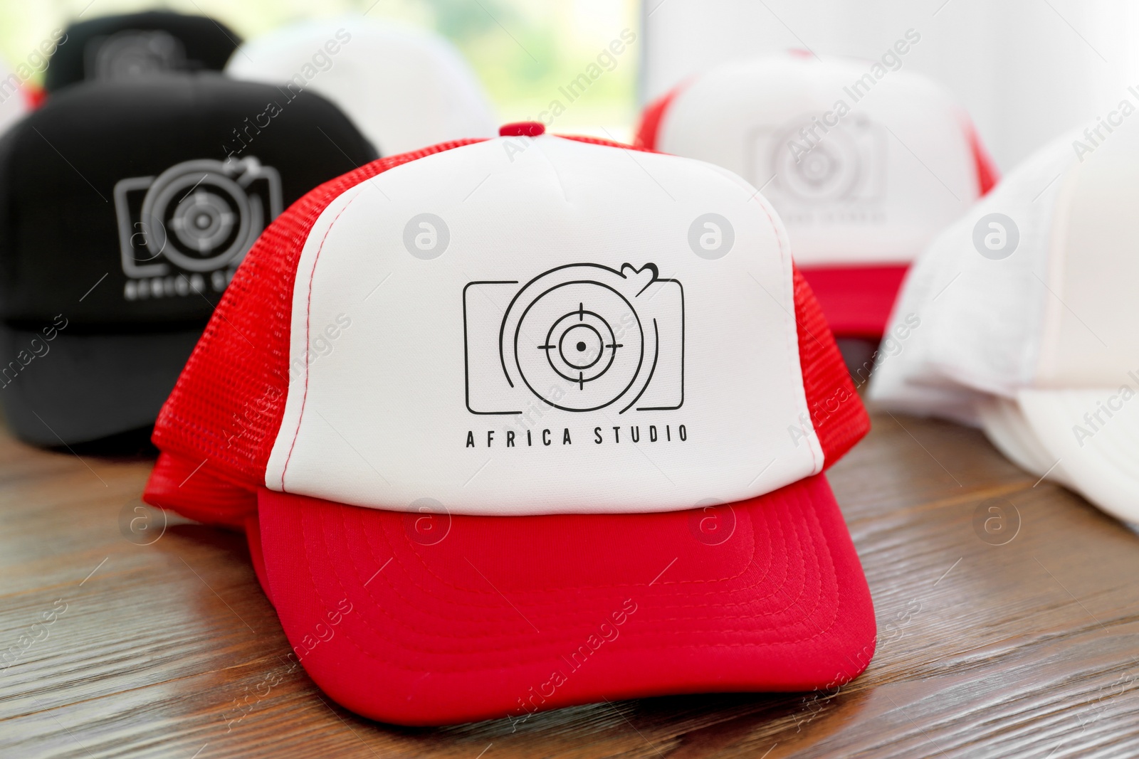 Photo of Different caps with logo on wooden table