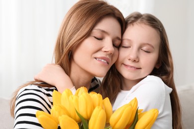 Photo of Mother and her cute daughter with bouquet of yellow tulips at home