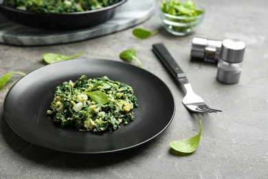 Photo of Plate with tasty spinach on grey table. Healthy food