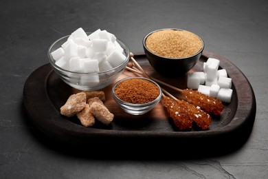 Different types of sugar on black table, closeup