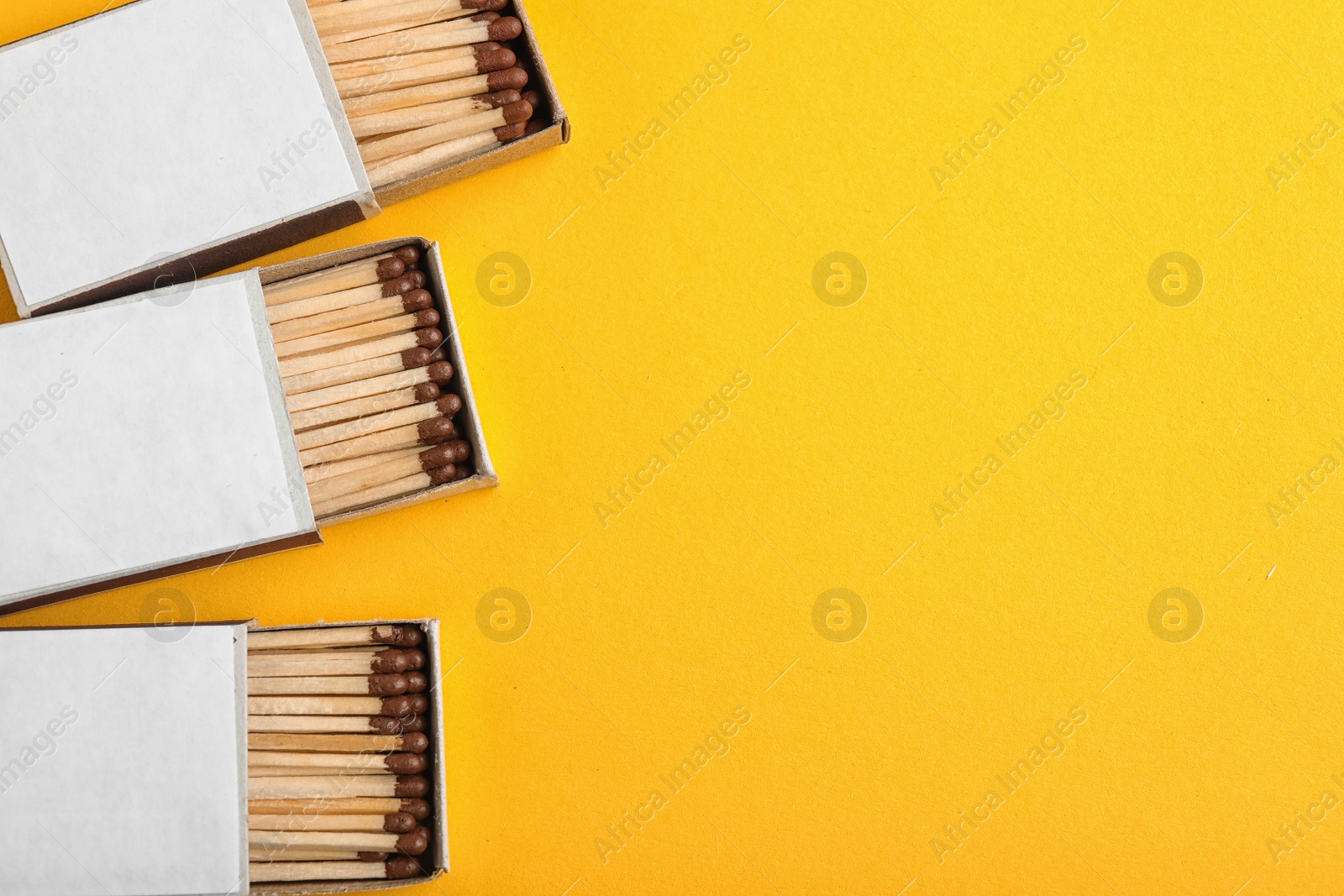 Photo of Cardboard boxes with matches on color background, flat lay. Space for text