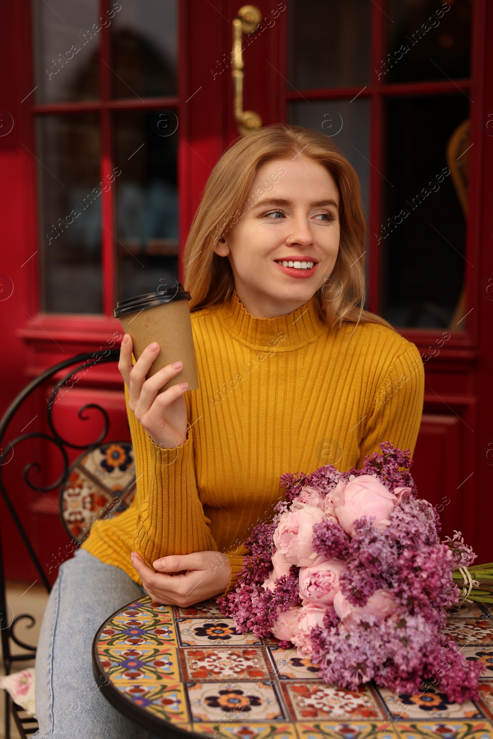 Photo of Beautiful woman with bouquet of spring flowers and coffee in outdoor cafe