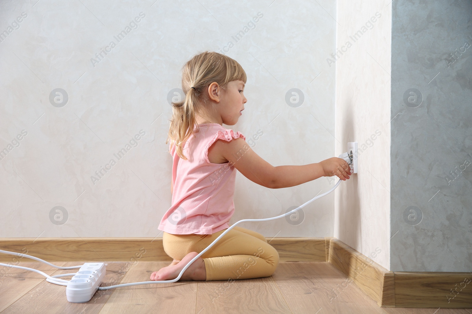 Photo of Little child playing with electrical socket and power strip plug at home. Dangerous situation