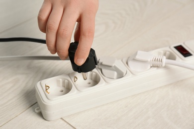 Woman inserting power plug into extension cord on floor, closeup. Electrician's professional equipment