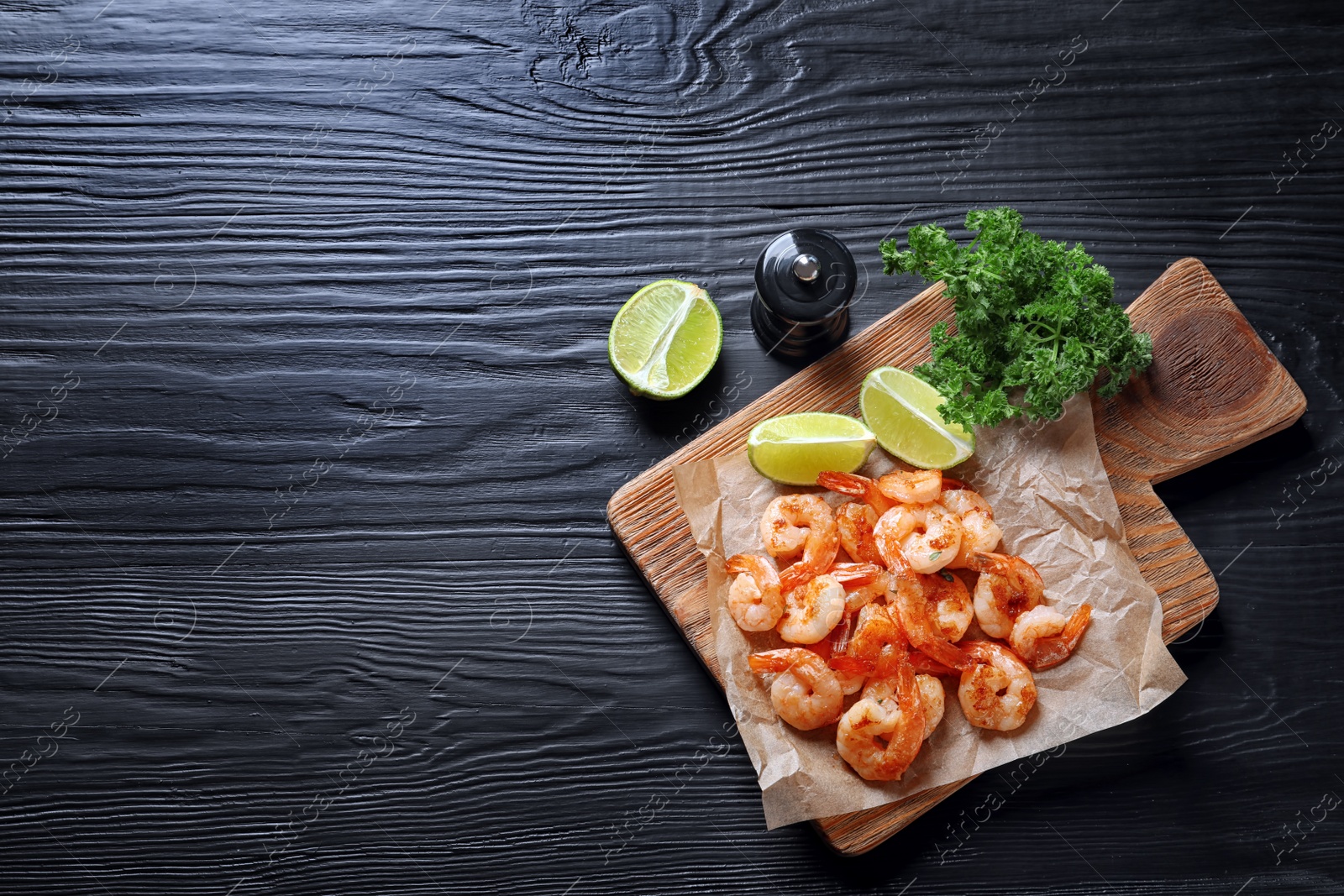 Photo of Board with delicious fried shrimps and lime on wooden background, top view