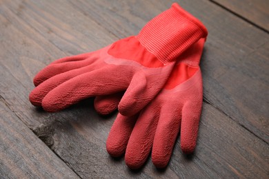 Photo of Pair of red gardening gloves on wooden table