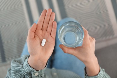 Photo of Young woman with abortion pill and glass of water, top view