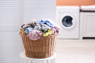 Photo of Wicker basket with dirty laundry in room
