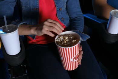 Photo of Young woman with popcorn watching movie in cinema, closeup