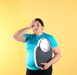 Photo of Overweight woman in sportswear with scales on color background