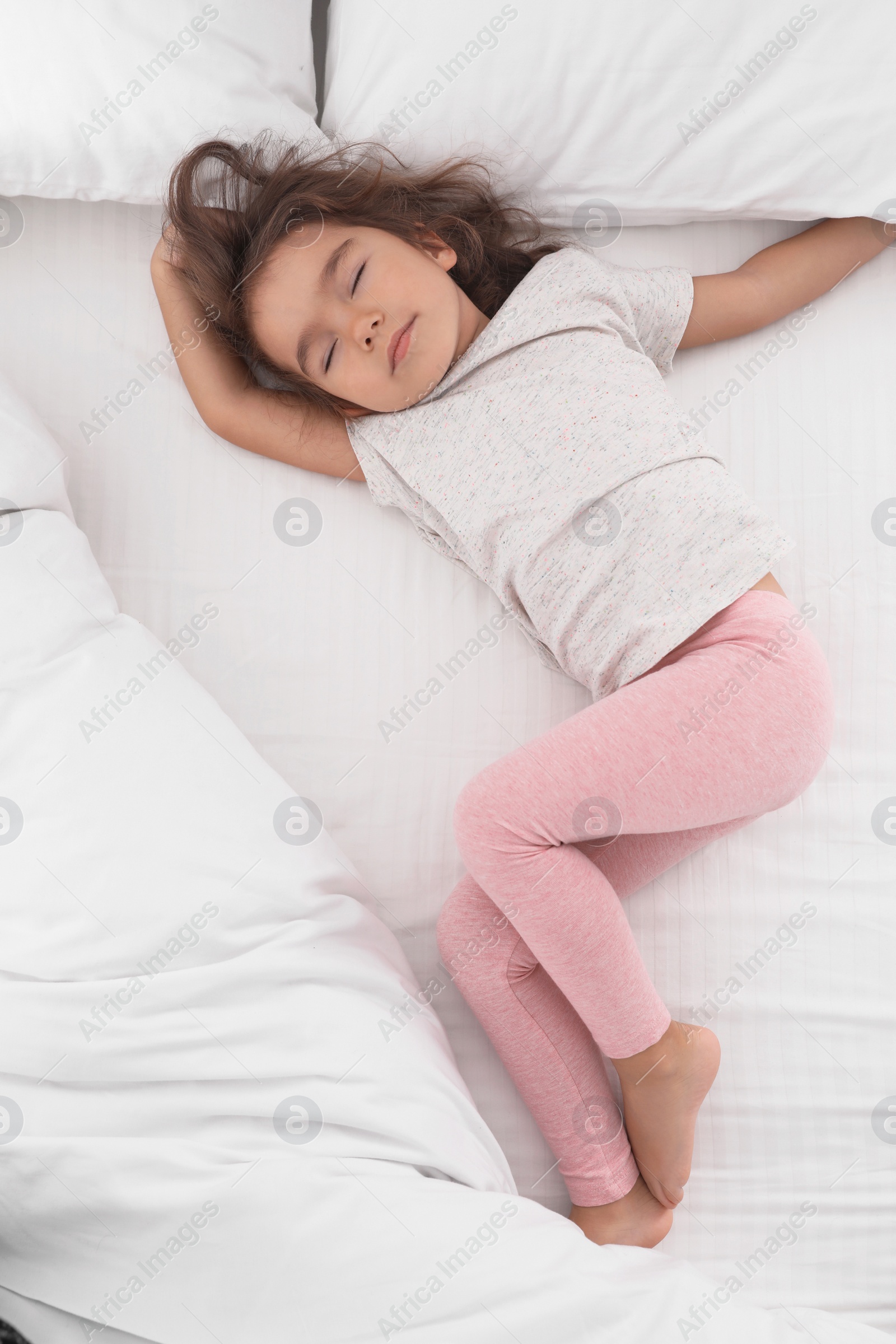 Photo of Cute little girl sleeping on cozy bed, view from above