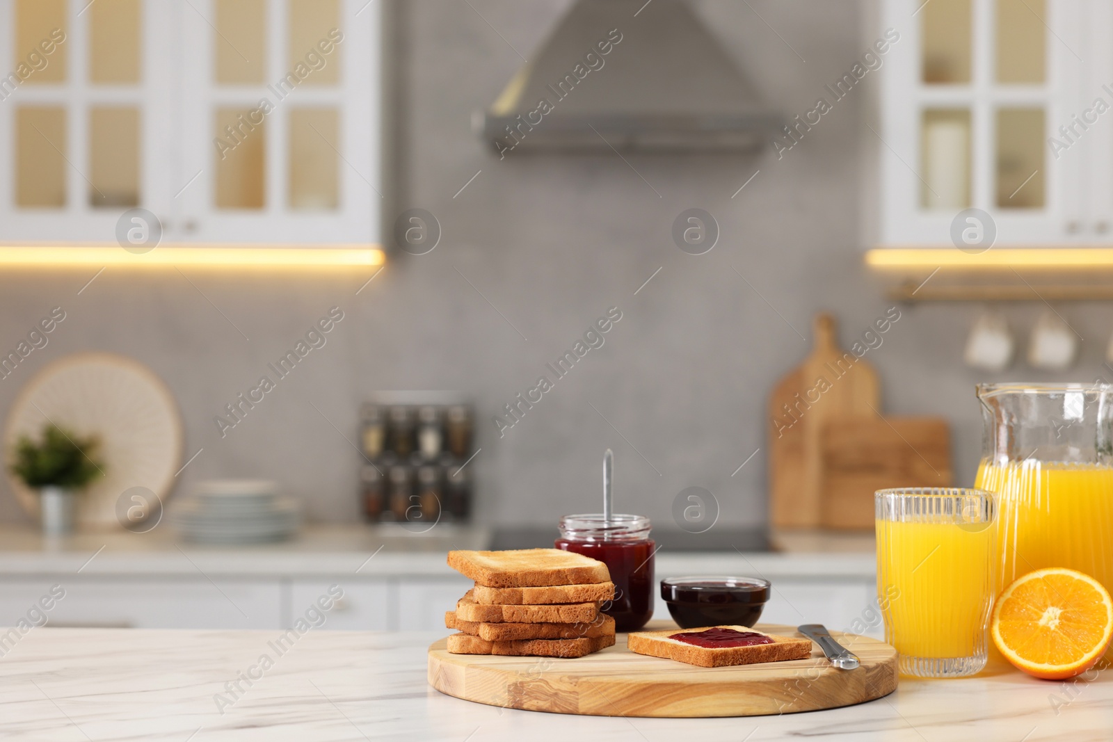 Photo of Breakfast served in kitchen. Crunchy toasts, jam and orange fresh on white table. Space for text