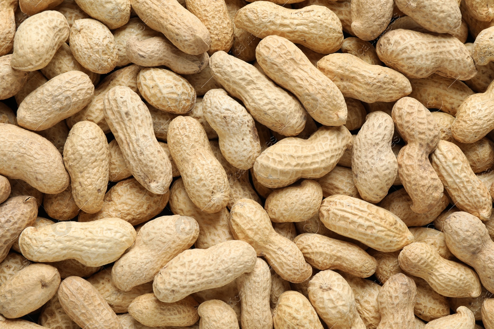 Photo of Many fresh unpeeled peanuts as background, top view