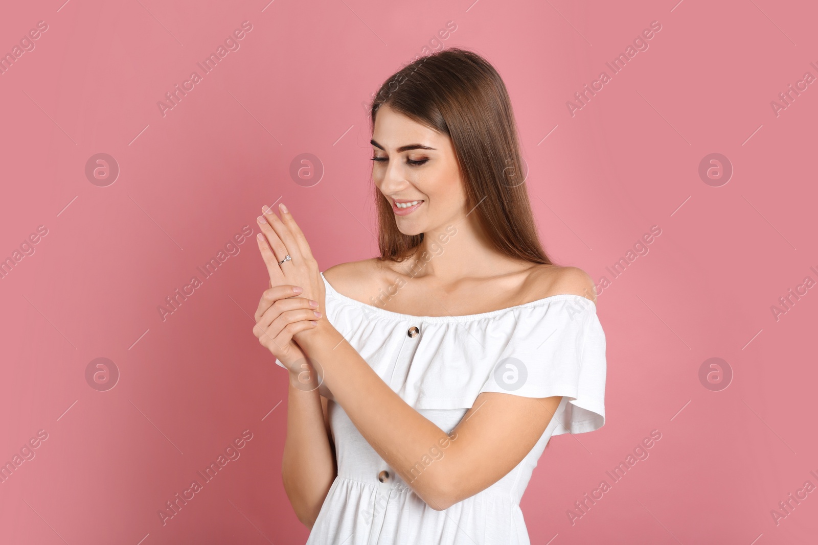 Photo of Happy young woman wearing beautiful engagement ring on pink background