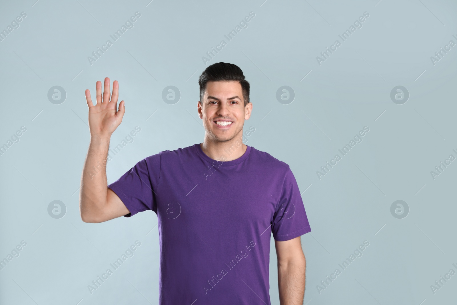 Photo of Cheerful man waving to say hello on grey background