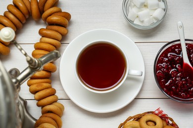 Photo of Flat lay composition with delicious ring shaped Sushki (dry bagels) and cup of tea on white wooden table