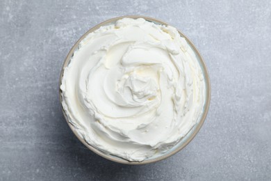 Photo of Bowl of tasty cream cheese on light grey table, top view