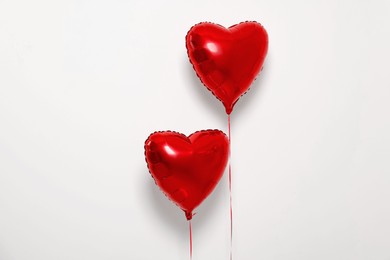 Red heart shaped balloons on white background, space for text