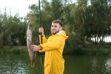 Photo of Man with rod and catch fishing at riverside. Recreational activity