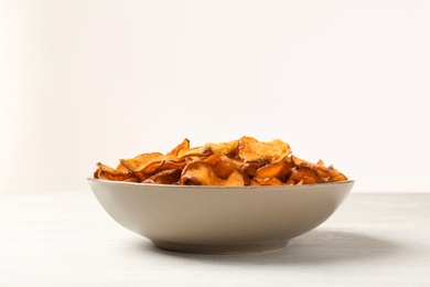 Photo of Plate of sweet potato chips on table against white background. Space for text