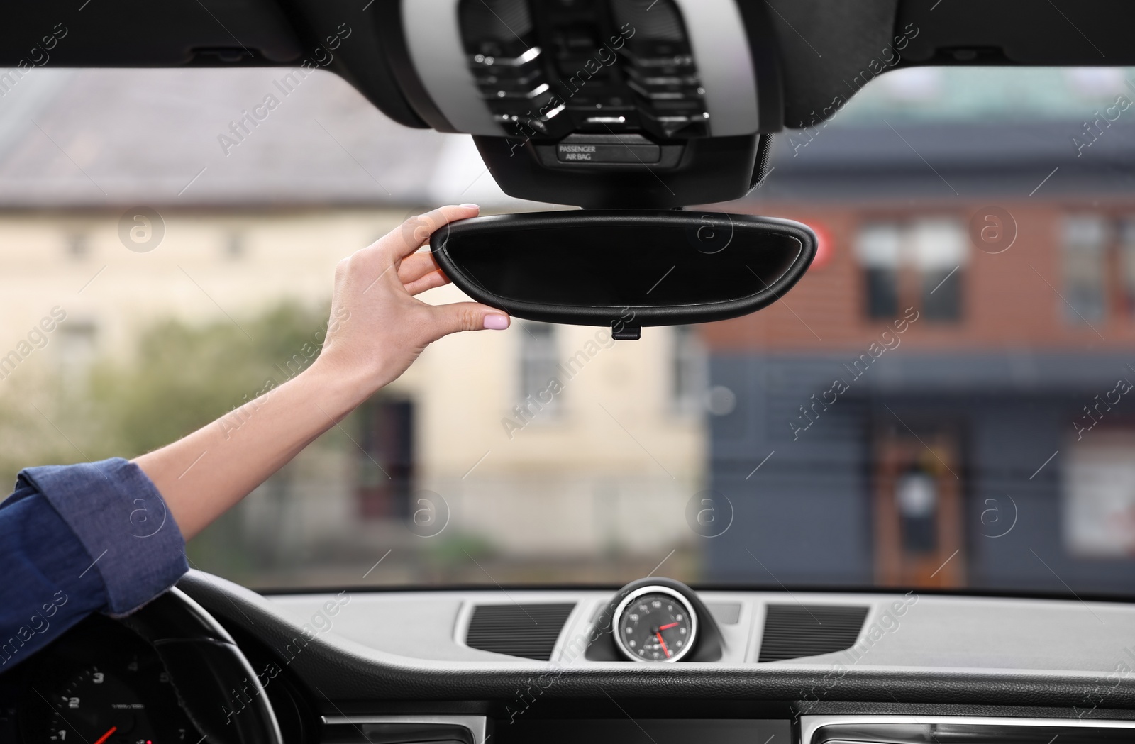 Photo of Woman adjusting rear view mirror inside her car, closeup