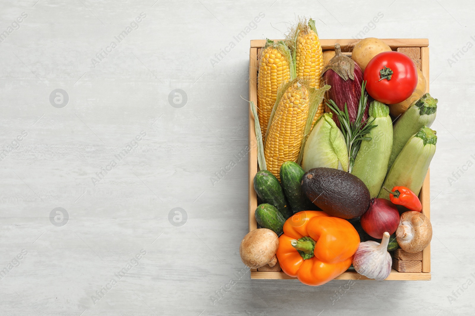 Photo of Crate with different fresh vegetables on light background, top view. Space for text