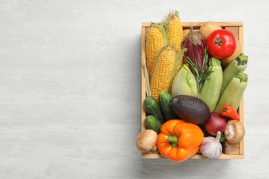 Crate with different fresh vegetables on light background, top view. Space for text