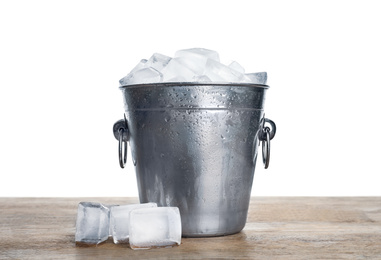 Metal bucket with ice cubes on wooden table against white background