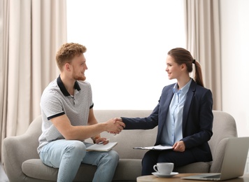 Female insurance agent shaking hands with young man in office