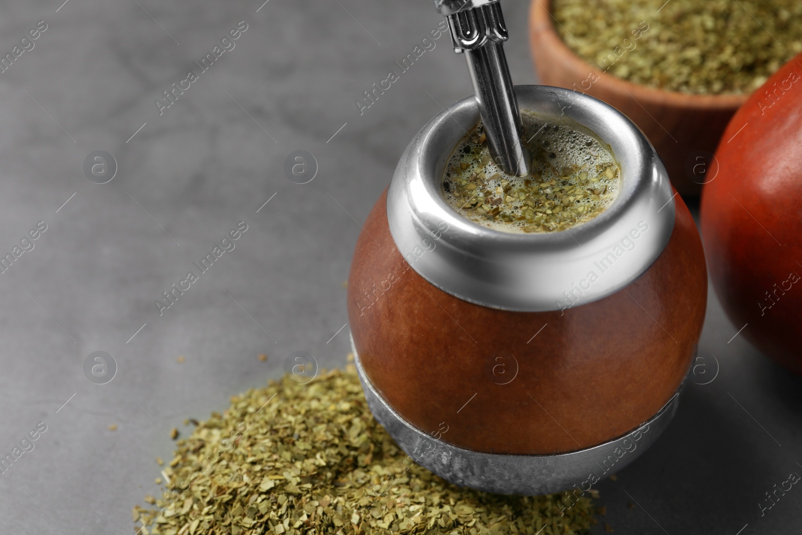 Photo of Calabash with mate tea and bombilla on light grey table, closeup. Space for text