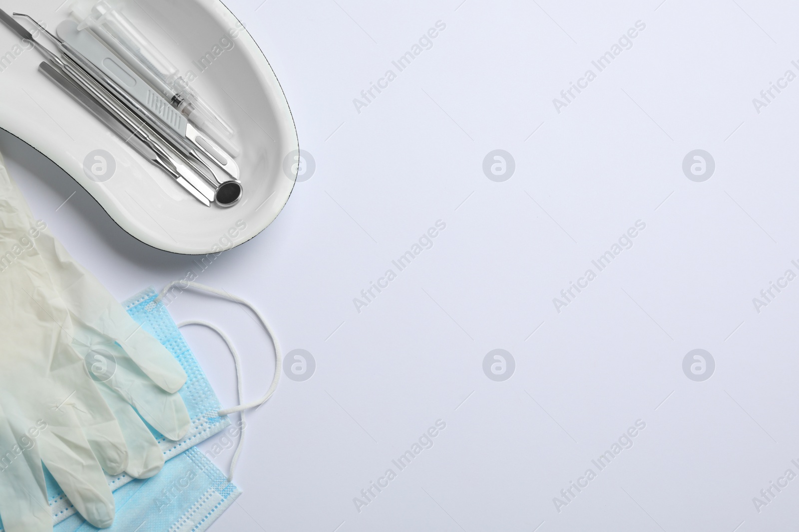 Photo of Set of different dentist's tools, face masks and gloves on light background, flat lay. Space for text