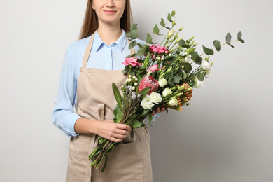 Photo of Florist with beautiful bouquet on light background, closeup