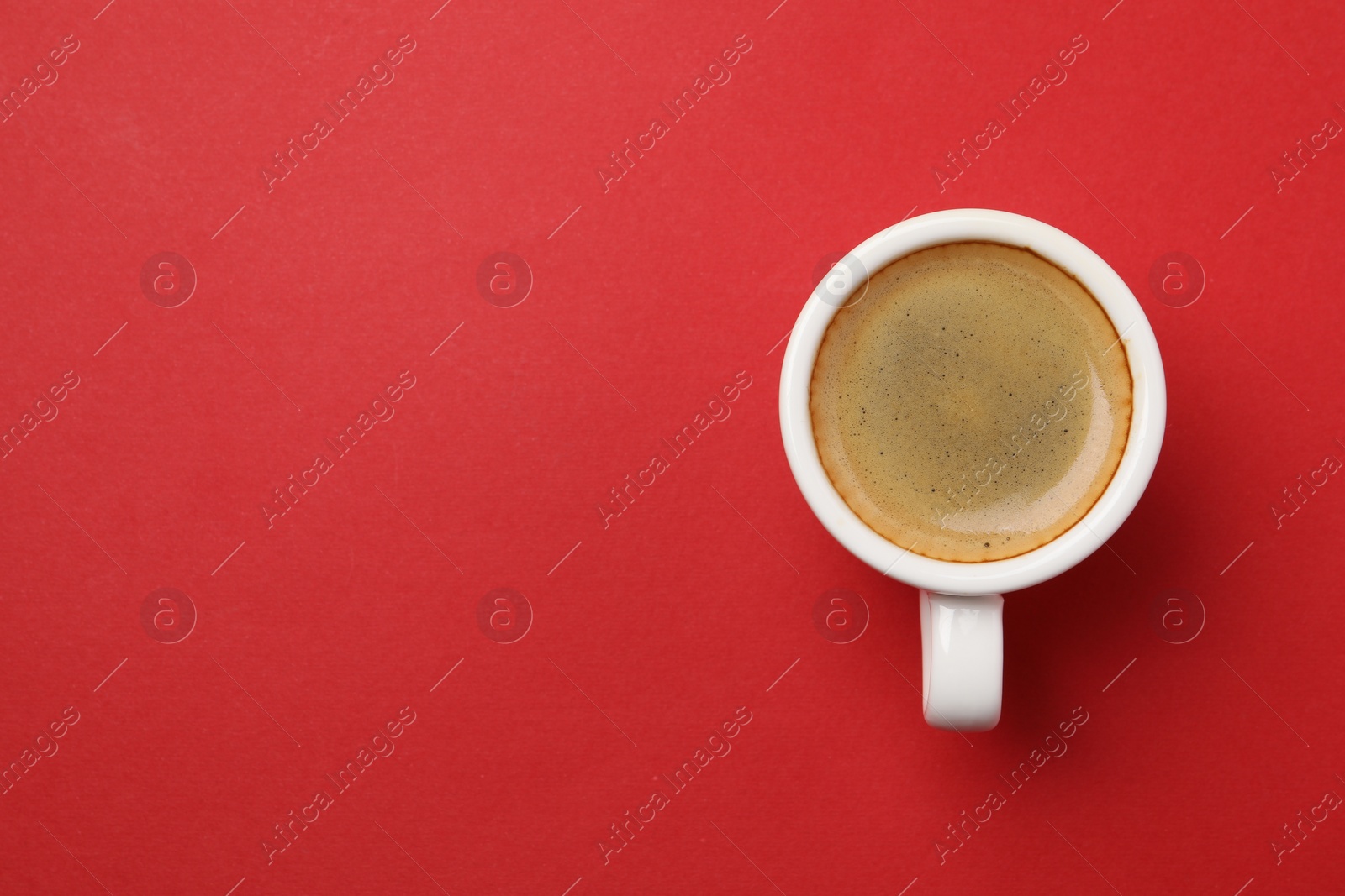 Photo of Aromatic coffee in cup on red background, top view. Space for text