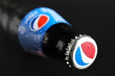 Photo of MYKOLAIV, UKRAINE - FEBRUARY 08, 2021: Glass bottle of Pepsi with water drops on black background, closeup