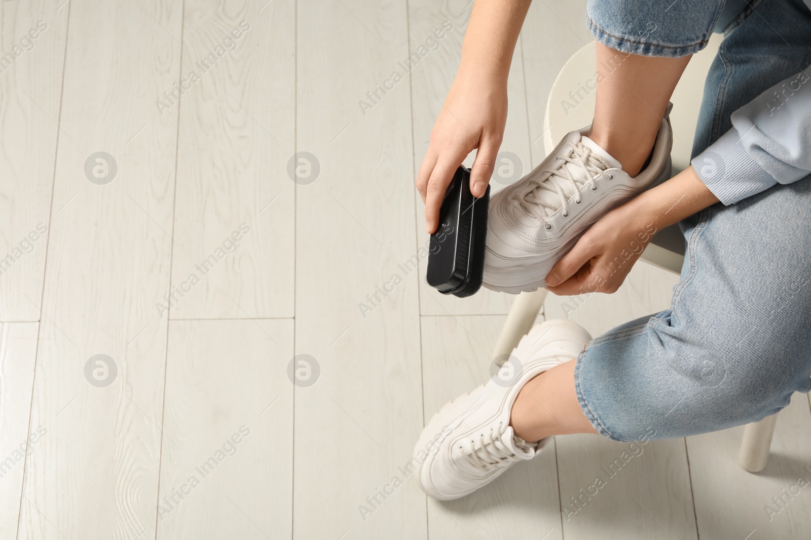 Photo of Woman cleaning stylish footwear indoors, closeup. Shoe care accessory