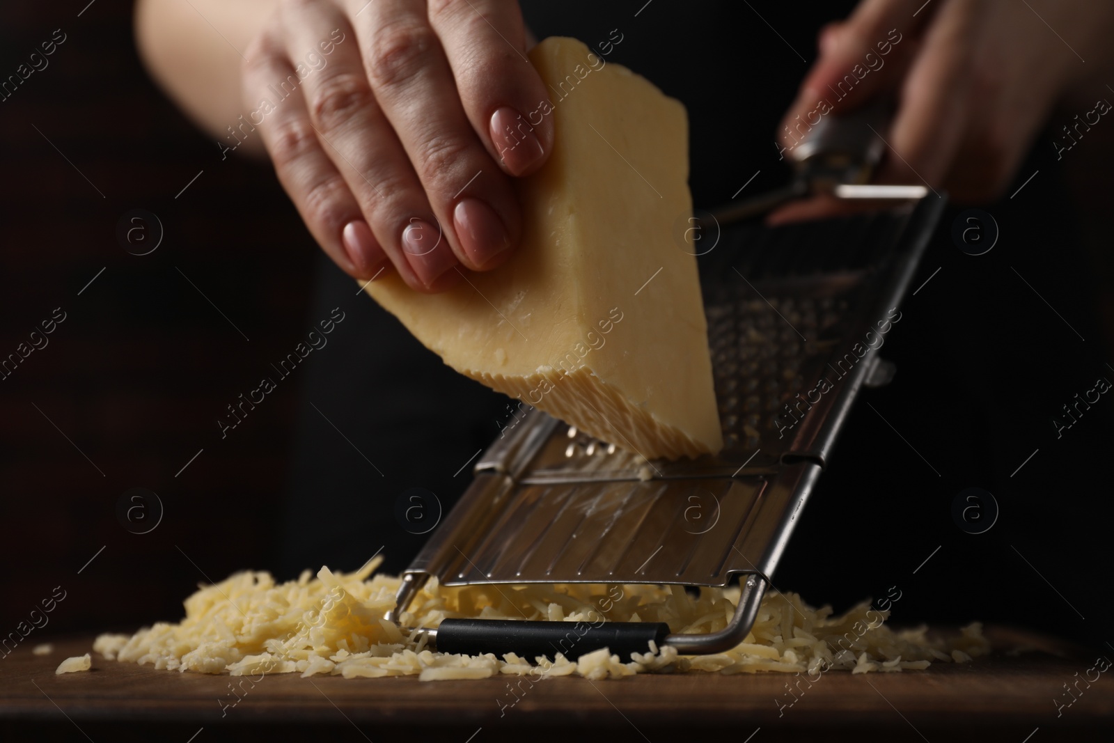 Photo of Woman grating cheese at wooden table, closeup