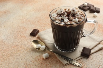 Photo of Cup of aromatic hot chocolate with marshmallows and cocoa powder served on beige table, closeup. Space for text