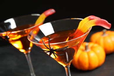 Photo of Decorated glasses with drinks on black background, closeup. Halloween celebration