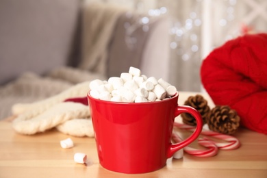 Photo of Cup of hot cocoa with marshmallows on wooden table indoors. Winter drink