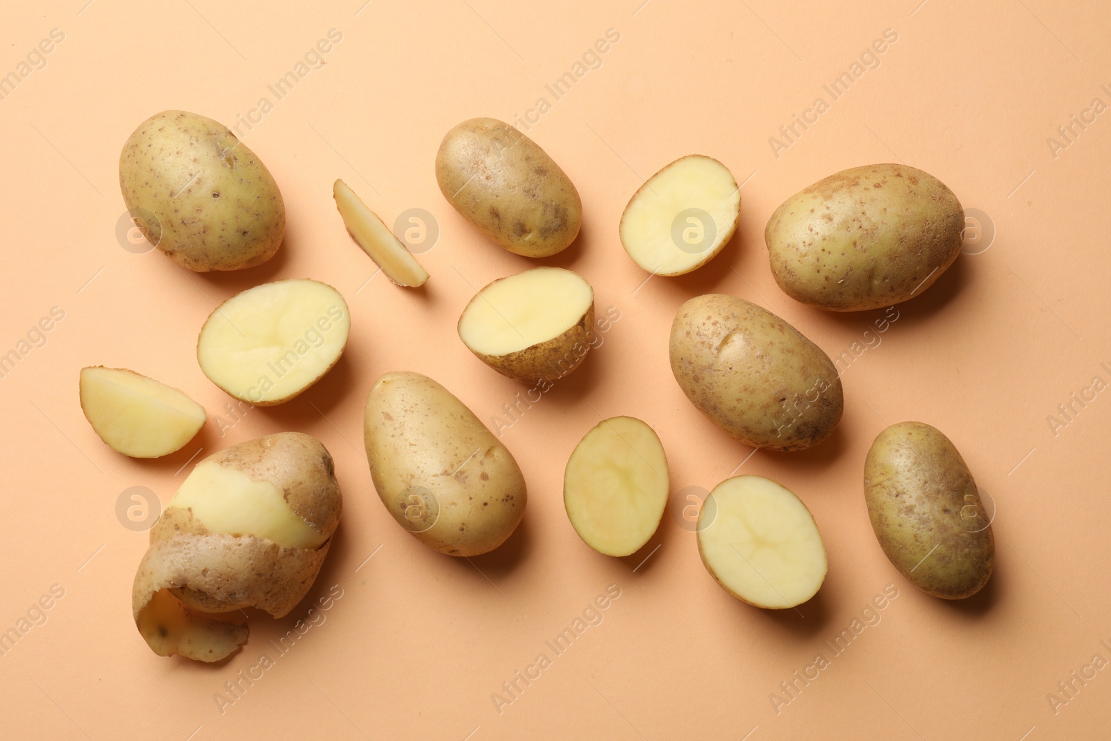 Photo of Fresh raw potatoes on pale orange background, flat lay