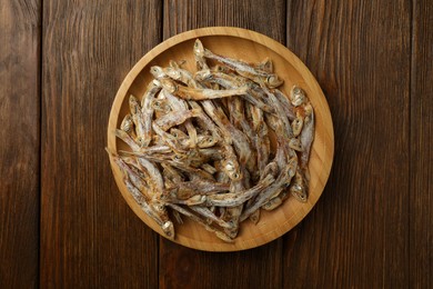 Photo of Tasty dried anchovies on wooden table, top view