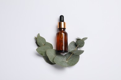 Aromatherapy product. Bottle of essential oil and eucalyptus leaves on white background, flat lay