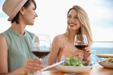 Photo of Young women with glasses of wine at table