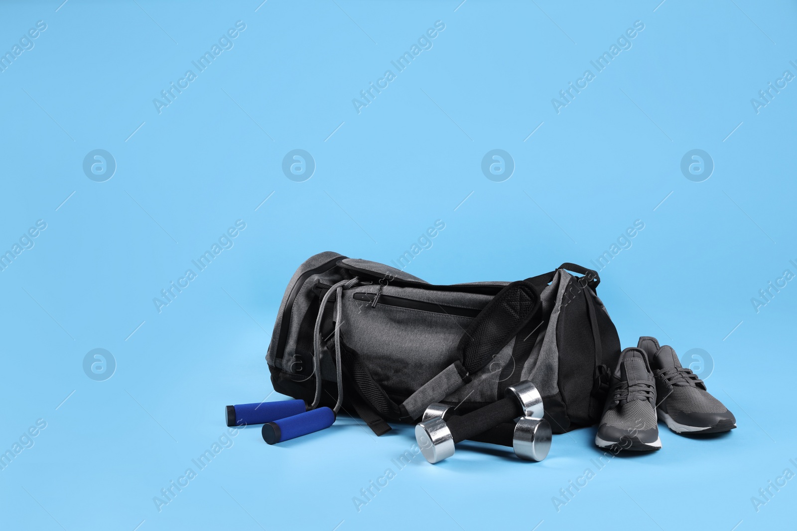 Photo of Grey bag and sports accessories on light blue background, space for text