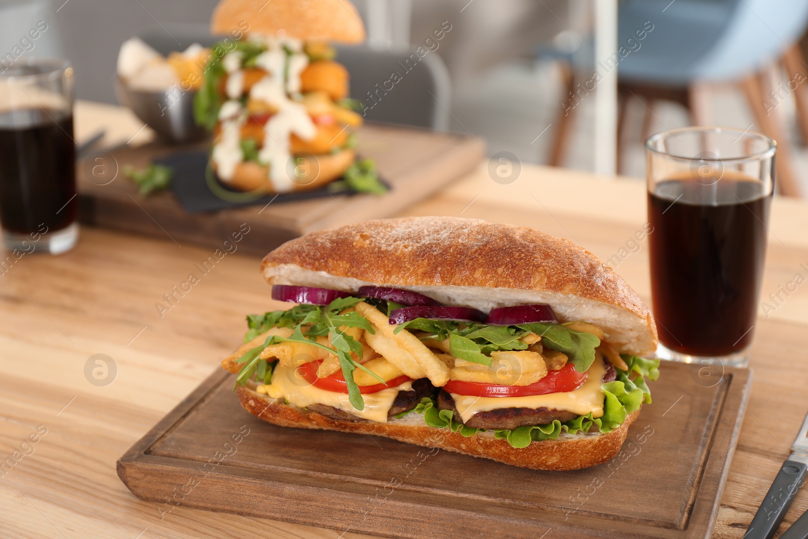 Photo of Wooden serving plate with yummy sandwich on table in cafe